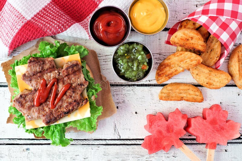 Plats för Kanada dagpicknick med den lönnlövhamburgaren och vattenmelon royaltyfri foto Plats för Kanada dagpicknick med den lönnlövhamburgaren och vattenmelon royaltyfri foto
