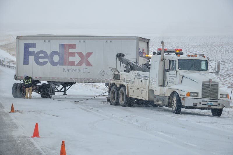 PLATTE NORTE, NEBRASKA - 25 de fevereiro de 2010 - caminhão de reboque prepara-se para retirar um reboque de Fedex a estrada gela imagem de stock PLATTE NORTE, NEBRASKA - 25 de fevereiro de 2010 - caminhão de reboque prepara-se para retirar um reboque de Fedex a estrada gela imagem de stock