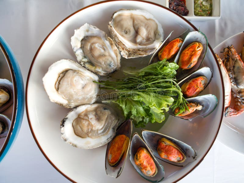 A platter of fresh organic raw oyster and Steam mussel on white table stock images