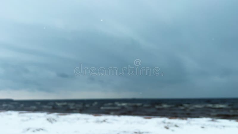 Playa de nieve desenfocada y mar frío. nieve cayendo a orillas del mar. viajar hacia el norte. partículas de papel tapiz borrosas