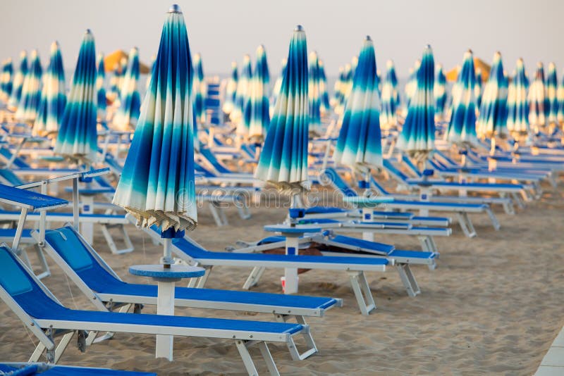 Rimini beach with blue sun umbrellas. Rimini, Italy. Rimini seashore. Tropical resort in Italy. Rimini beach with blue sun umbrellas. Rimini, Italy. Rimini seashore. Tropical resort in Italy