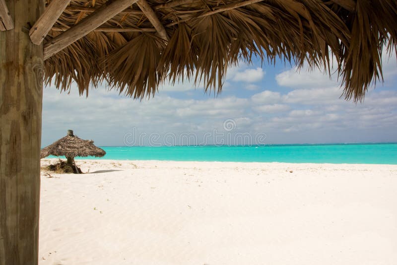 Tropical unspoilt beach from under thatched sunshade. Tropical unspoilt beach from under thatched sunshade