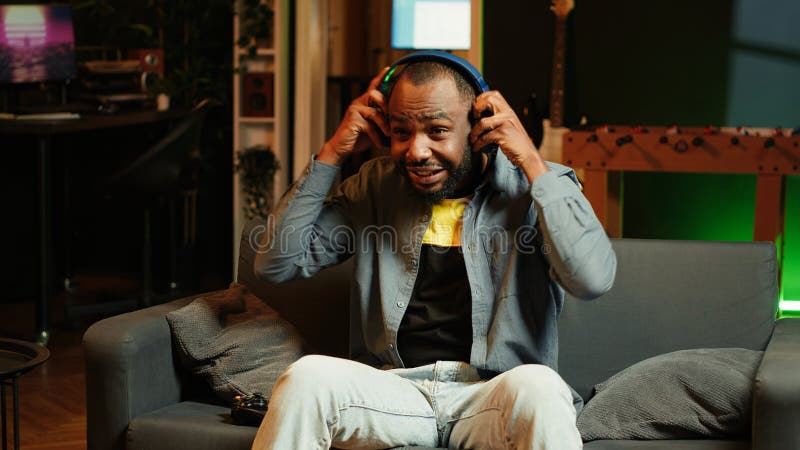 Player on couch putting headphones on to be immersed in videogame experience stock image