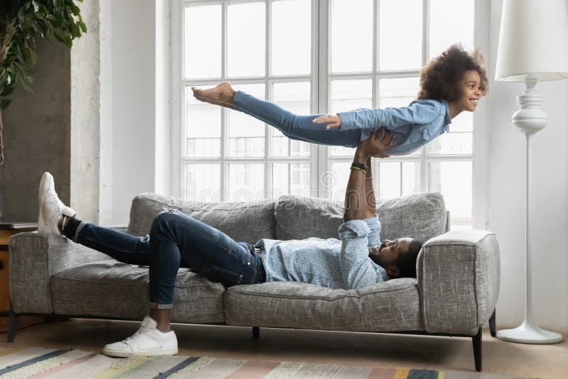 Playful african American dad and daughter play at home