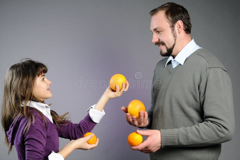 Playful father and daughter playing with oranges