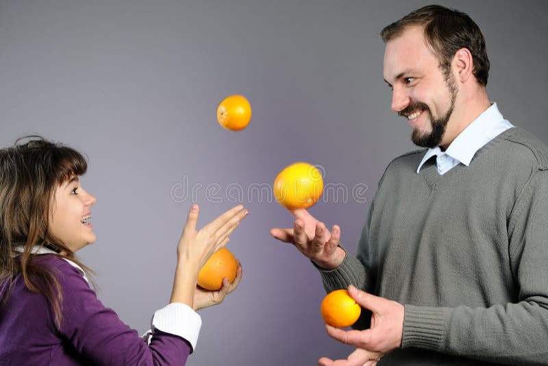 Playful father and daughter playing with oranges