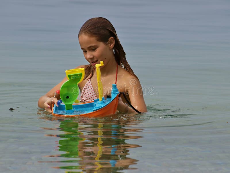 Young girl playing with plastic toy boat in the Adriatic sea (Croatia-Dalmatia). Young girl playing with plastic toy boat in the Adriatic sea (Croatia-Dalmatia)