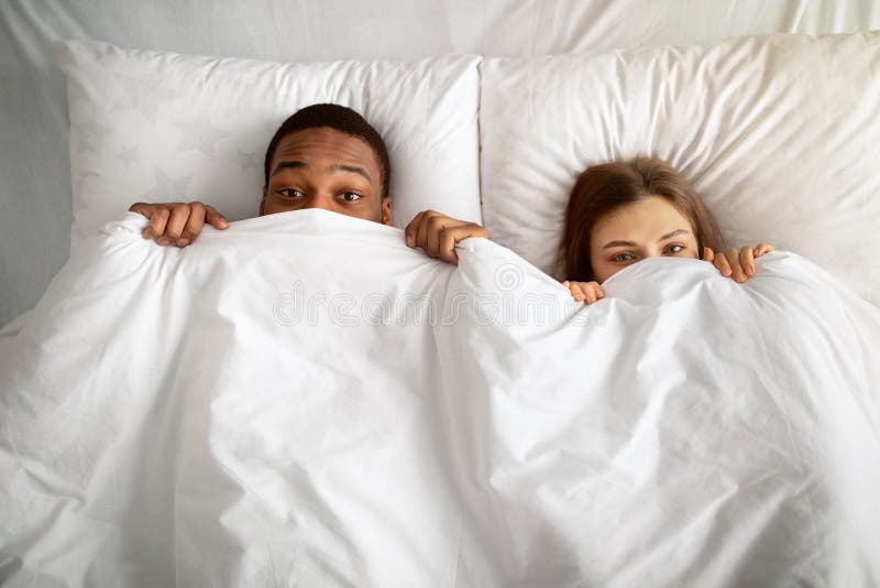 Playful Interracial Couple Hiding Under White Blanket In Bed Top View Stock Image Image Of