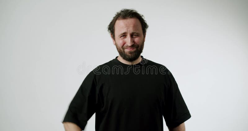 Playful Man in Black TShirt Winks and Laughs at Camera on White Background stock footage