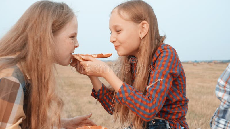 Playful teenager girls eating pizza for two on countryside field on haystack background. Cheerful teenager friends stock video footage Playful teenager girls eating pizza for two on countryside field on haystack background. Cheerful teenager friends stock video footage