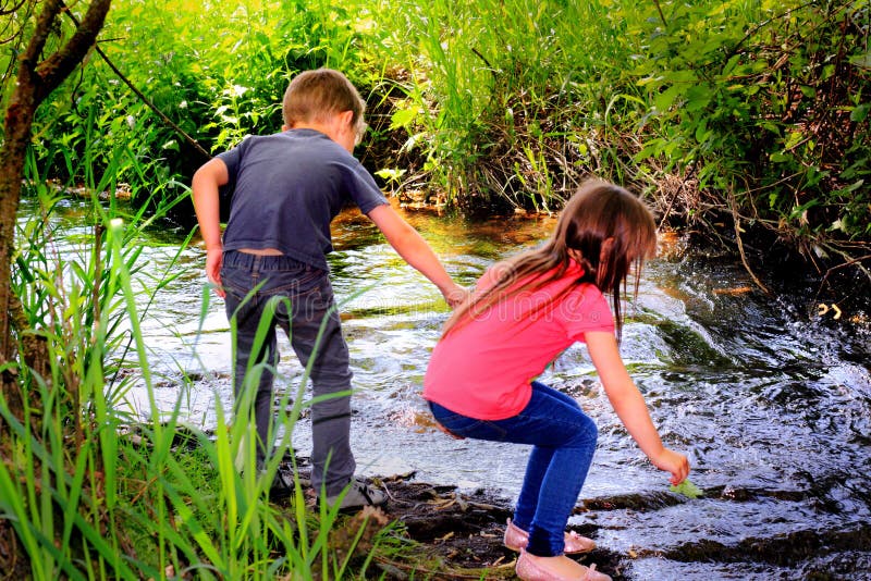 Two little kids exploring and playing by a stream in the woods. Shallow depth of field.