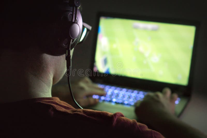 lazy teenager boy play computer games, sit in headphones, looking at screen  of laptop, free time at home Stock Photo