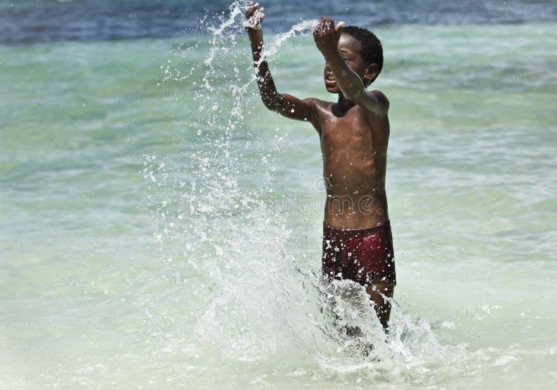Bahamas ragazzo a giocare con l'acqua alla spiaggia.