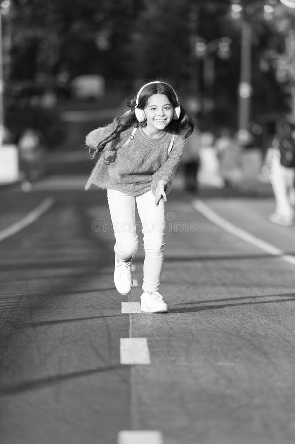 Playlist for active day. Girl cute with headphones. Little child enjoy activity. Kid walking running in park listening royalty free stock images Playlist for active day. Girl cute with headphones. Little child enjoy activity. Kid walking running in park listening royalty free stock images
