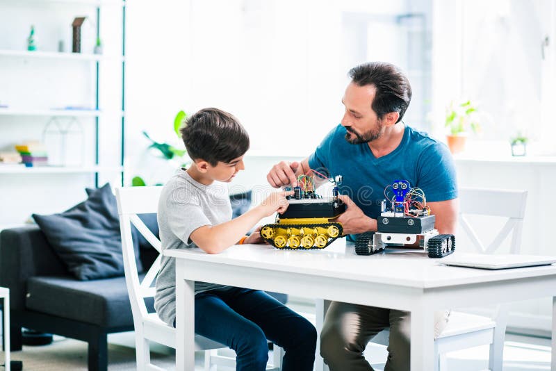 Involved man and his little son constructing robotic devices royalty free stock images