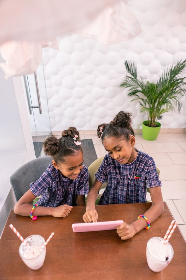 Top view of pleasant cute sisters watching cartoon while sitting in bakery stock images Top view of pleasant cute sisters watching cartoon while sitting in bakery stock images