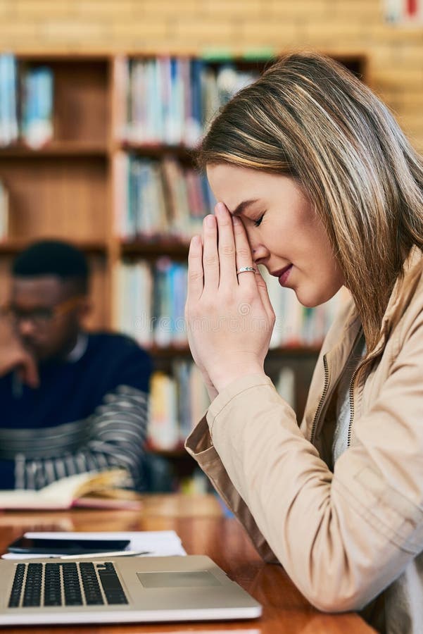 Please dont let me fail this test... a young woman looking stressed while sitting behind a laptop. royalty free stock photos