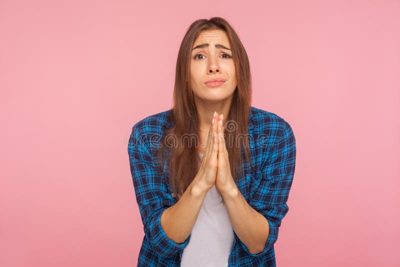 Please! Portrait of girl in checkered shirt holding hands in prayer, looking with imploring pleading expression