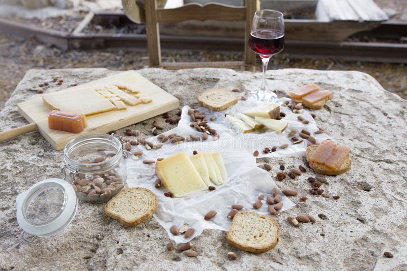 Please sit down and eat. Empty chair in front of variety of cheese