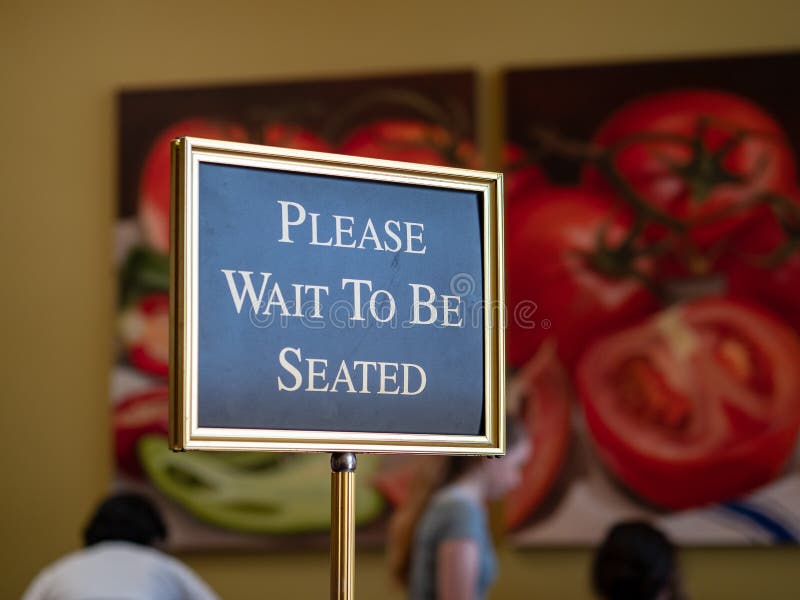 Please wait to be seated sign standing at the front of a restaurant