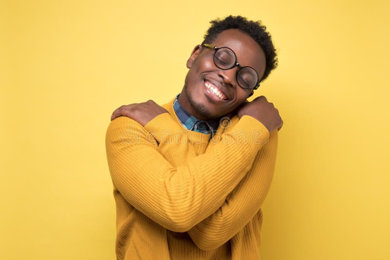 Pleased african american man hugs himself, has high self esteem. Pleased african american man in yellow clothes and glasses hugs himself, has high self esteem stock photography Pleased african american man hugs himself, has high self esteem. Pleased african american man in yellow clothes and glasses hugs himself, has high self esteem stock photography