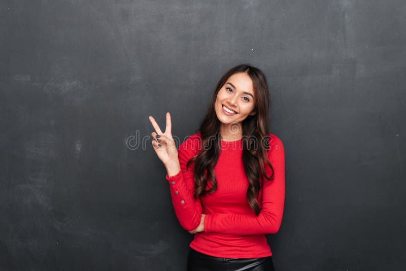 Pleased brunette woman in red blouse showing peace gesture stock photography Pleased brunette woman in red blouse showing peace gesture stock photography