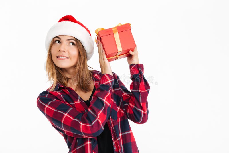 Pleased brunette woman in shirt and christmas hat holding gift royalty free stock image Pleased brunette woman in shirt and christmas hat holding gift royalty free stock image