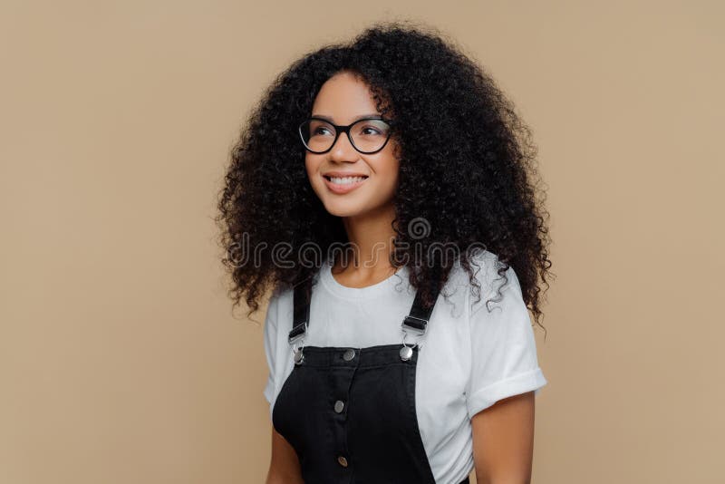 Pleased Dreamy Woman with Curly Hairstyle, Looks through Transparent  Glasses, Dressed in Casual White T Shirt and Black Dungarees Stock Image -  Image of eyewear, outfit: 159515845