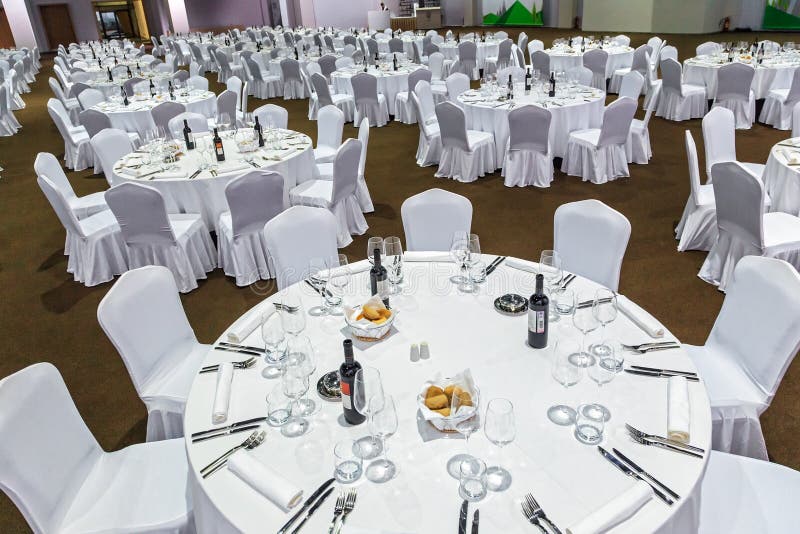 Plenty of big round tables and chairs covered with white tablecloth are set for a meal in the Gorky Gorod restaurant. Wide angle i