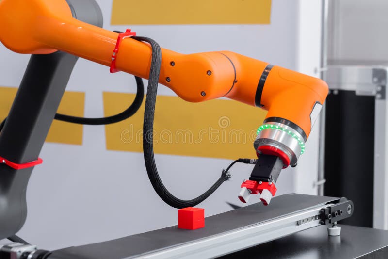 Plocka och placera manipulatorer för robotar som flyttar röda leksaksblock vid robotutställningen. Rangefärgad plockning och placering av manipulator för robotklämmor för att flytta röda leksaksblock vid den moderna utställningen för robothandel. Industriellt automatiserat teknikkoncept inom tillverkningsindustrin