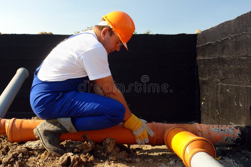 Plumber assembling pvc sewage pipes in house foundation. Plumber assembling pvc sewage pipes in house foundation