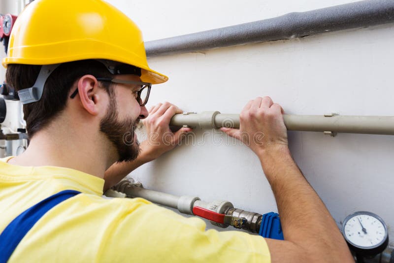 Plombier travaillant avec des canalisations images stock Plombier travaillant avec des canalisations images stock
