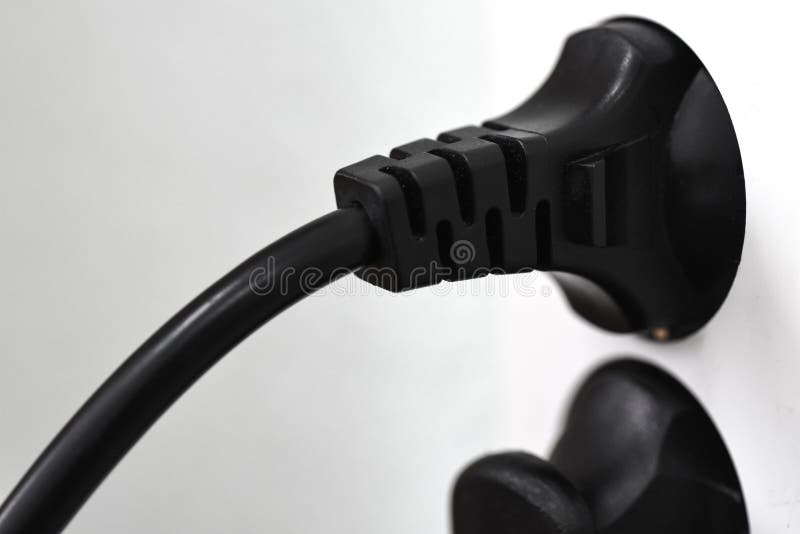 A Plug in the Cord is Plugged into an Electrical Outlet Stock Photo