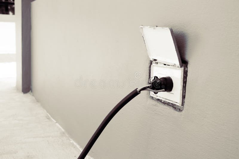 The Plug is Plugged into a Wall Outlet at Outside of House Stock Image