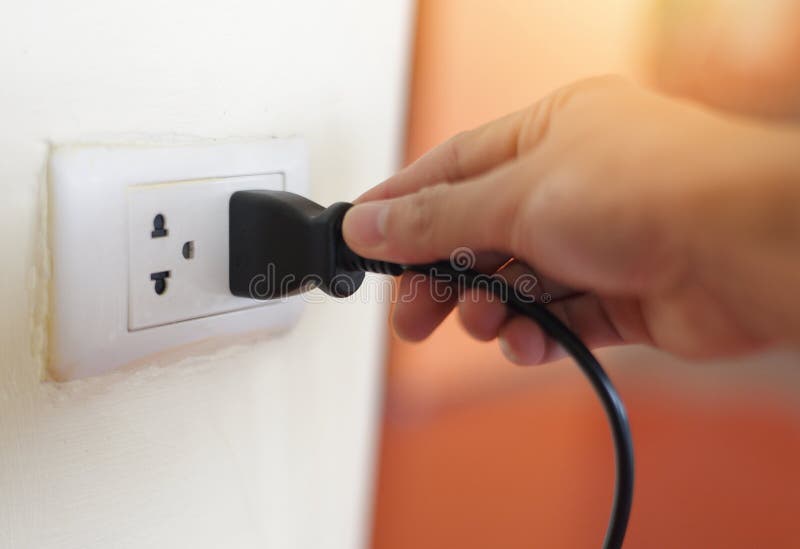 Plug in Wall with Hand and Black Power Cord Cable Unplug or Plugged in Concept Socket on