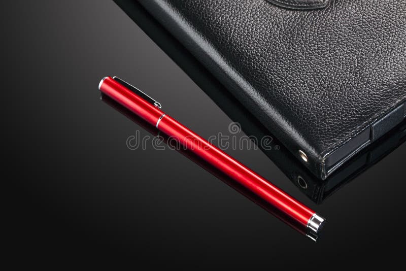 Pluma roja y cuaderno de cuero negro sobre el vidrio fotografía de archivo libre de regalías Pluma roja y cuaderno de cuero negro sobre el vidrio fotografía de archivo libre de regalías
