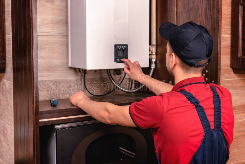 Plumber adjusts gas boiler before operating royalty free stock photo Plumber adjusts gas boiler before operating royalty free stock photo