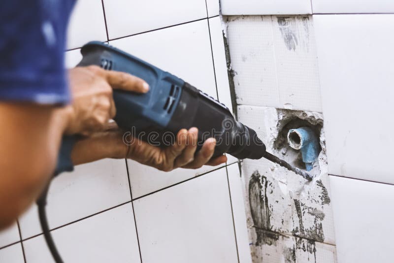 Plumber drilling water pipe in toilet