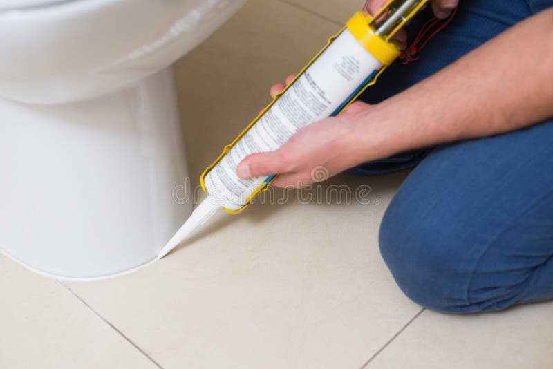 Plumber fixing toilet in a washroom with silicone cartridge royalty free stock images Plumber fixing toilet in a washroom with silicone cartridge royalty free stock images