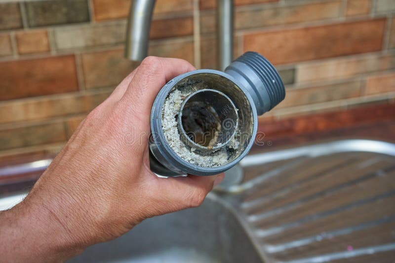 A Plumber Holds a Clogged Siphon, Hand of Plumber Holding the Siphon Above the Sink is Clogged
