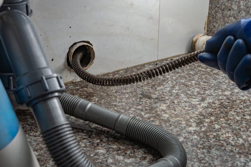 Plumber Using Equipment To Remove Grease from Drain Pipe Stock Image