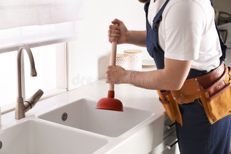 Plumber using plunger to unclog sink drain in kitchen, closeup royalty free stock images