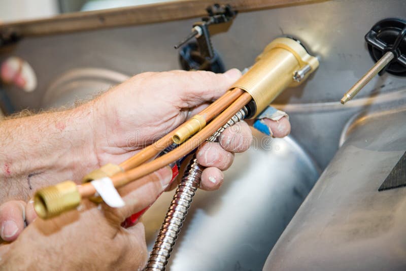 Primo piano di un idraulici mani l'installazione di un rubinetto di un lavandino.