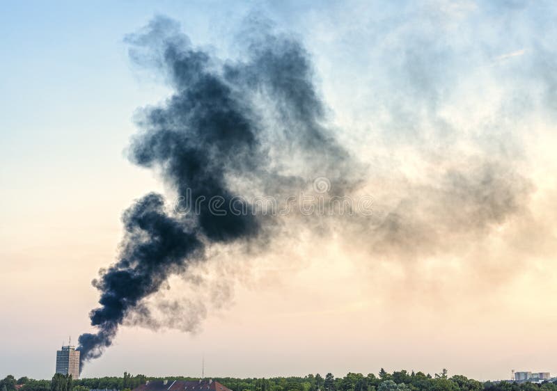 Plume of smoke from a fire above city at sunset