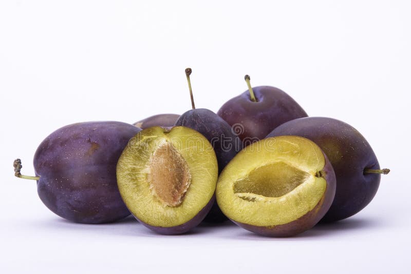 Plums on white background with halved one