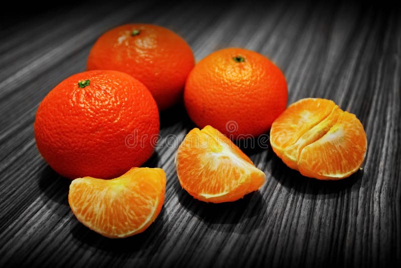 Plusieurs mandarines mûres fraîches et tranches épluchées de mandarine sur la surface en bois image stock Plusieurs mandarines mûres fraîches et tranches épluchées de mandarine sur la surface en bois image stock