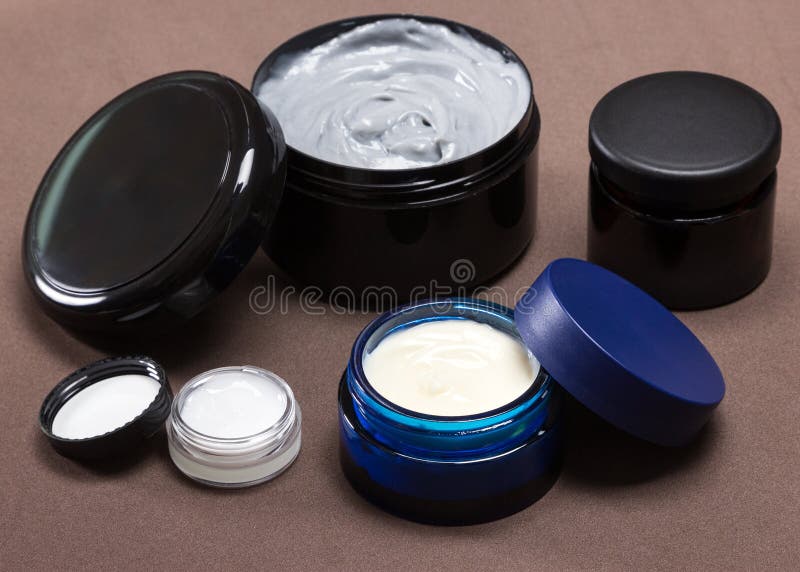 Several jars of different sizes filled with creams on brown background. Various skin care cosmetic products. Cosmetics with natural ingredients. Skincare for men. Several jars of different sizes filled with creams on brown background. Various skin care cosmetic products. Cosmetics with natural ingredients. Skincare for men