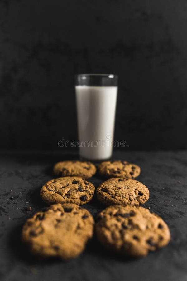 Plätzchen mit Schokoladenschiffen und -milch mit einem dunklen Hintergrund stockfoto Plätzchen mit Schokoladenschiffen und -milch mit einem dunklen Hintergrund stockfoto