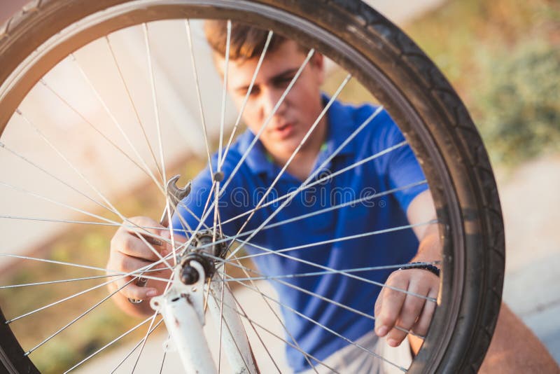 Pneu de réparation de garçon d'adolescent sur la bicyclette photographie stock Pneu de réparation de garçon d'adolescent sur la bicyclette photographie stock