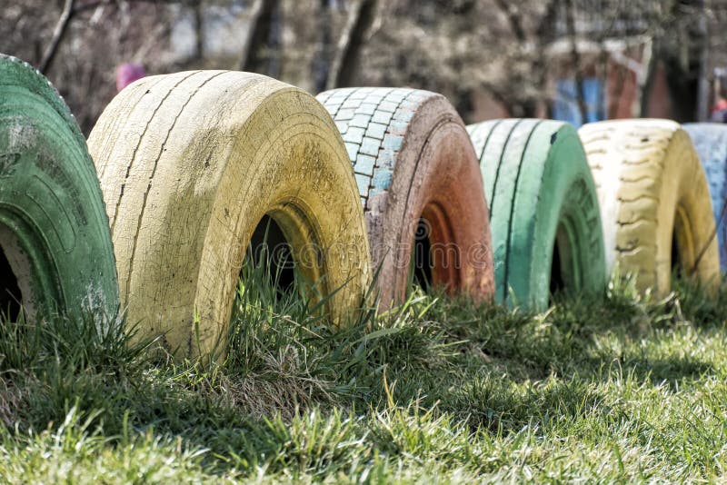 Pneus de caminhão usados no solo como vedações e pintados em cores diferentes fotos de stock Pneus de caminhão usados no solo como vedações e pintados em cores diferentes fotos de stock